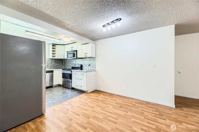 921 130th St SW Unit E102, Everett, WA 98204 - kitchen with stainless steel appliances, light wood finished floors, backsplash, white cabinets, and light countertops