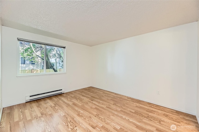 921 130th St SW Unit E102, Everett, WA 98204 - unfurnished room featuring a baseboard heating unit, light wood-type flooring, and a textured ceiling