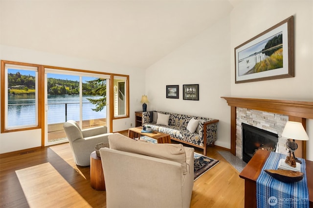 115 Quarry Rd, Port Ludlow, WA 98365 - living room with vaulted ceiling, wood finished floors, a stone fireplace, and a water view