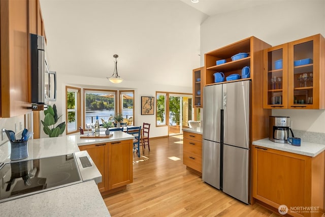 115 Quarry Rd, Port Ludlow, WA 98365 - kitchen with freestanding refrigerator, brown cabinetry, light wood finished floors, stovetop, and glass insert cabinets