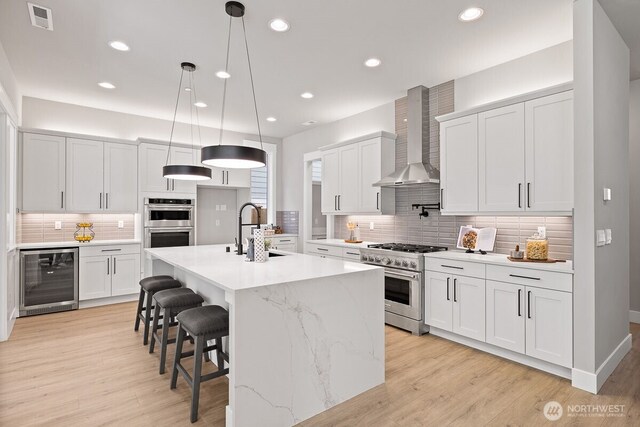 1418 238th St SE, Bothell, WA 98021 - kitchen with beverage cooler, appliances with stainless steel finishes, wall chimney exhaust hood, tasteful backsplash, and light wood finished floors