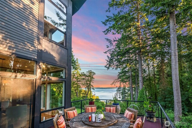 182 Island Blvd, Fox Island, WA 98333 - balcony at dusk featuring a water view and outdoor dining space