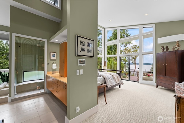 182 Island Blvd, Fox Island, WA 98333 - bedroom featuring a towering ceiling, a water view, expansive windows, connected bathroom, and tile patterned floors