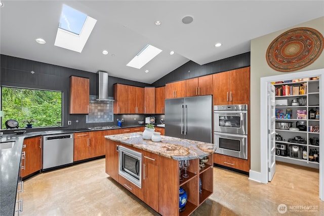 182 Island Blvd, Fox Island, WA 98333 - kitchen featuring stainless steel appliances, a skylight, wall chimney exhaust hood, a center island, and brown cabinets