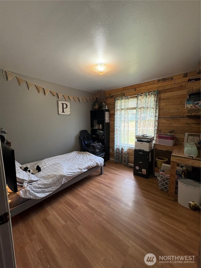 47 Pinecrest Rd, Tonasket, WA 98855 - bedroom with wood finished floors, a textured ceiling, and wood walls