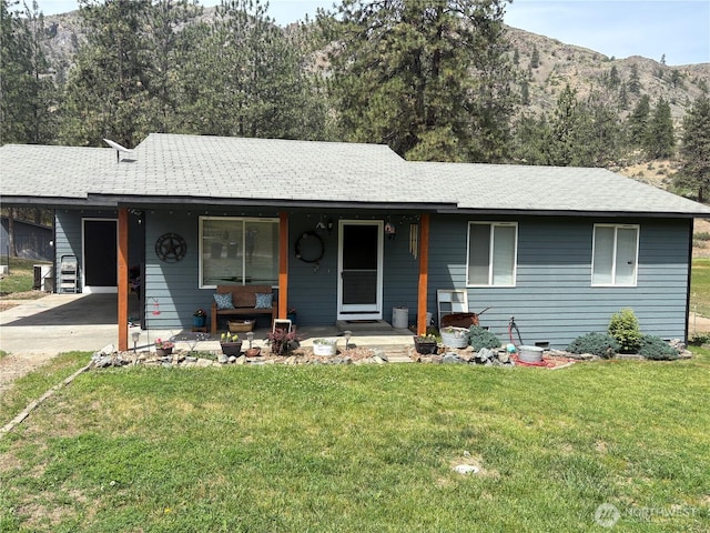 47 Pinecrest Rd, Tonasket, WA 98855 - ranch-style house featuring covered porch, an attached carport, a front yard, driveway, and roof with shingles