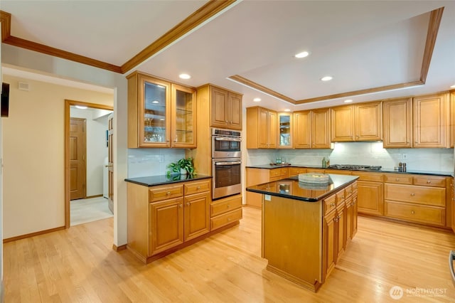 4920 Seahurst Ave, Everett, WA 98203 - kitchen with a raised ceiling, stainless steel appliances, dark countertops, a kitchen island, and light wood-style flooring