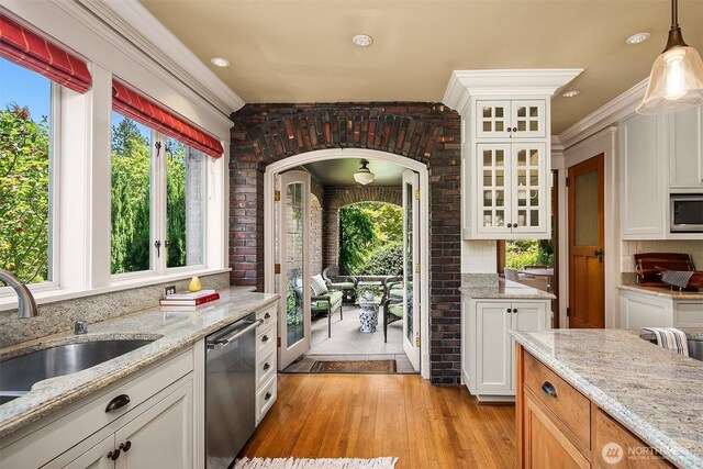 3804 S Mcclellan St, Seattle, WA 98144 - kitchen featuring appliances with stainless steel finishes, light wood finished floors, healthy amount of natural light, white cabinetry, and brick wall