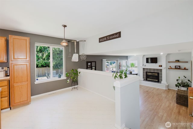 7315 E Collins Rd, Port Orchard, WA 98366 - kitchen featuring healthy amount of natural light, a tiled fireplace, light wood-type flooring, and decorative light fixtures