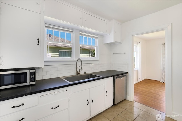 221 Thomas St N, Olympia, WA 98502 - kitchen featuring stainless steel appliances, dark countertops, decorative backsplash, light tile patterned flooring, and white cabinetry