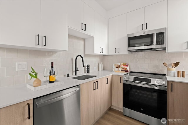 1525 N 39th St, Seattle, WA 98103 - kitchen featuring stainless steel appliances, light countertops, backsplash, light wood-style floors, and white cabinets