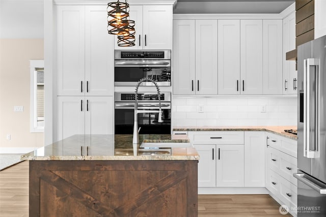 821 S Mary Ave, East Wenatchee, WA 98802 - kitchen featuring appliances with stainless steel finishes, light wood-style floors, white cabinets, light stone countertops, and decorative backsplash