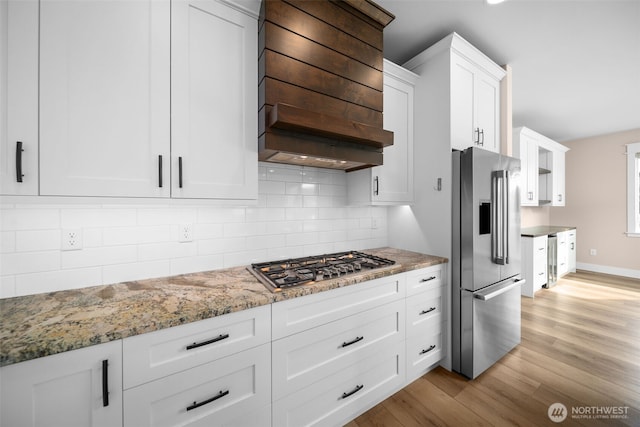 821 S Mary Ave, East Wenatchee, WA 98802 - kitchen featuring appliances with stainless steel finishes, custom exhaust hood, white cabinets, light wood-type flooring, and light stone countertops