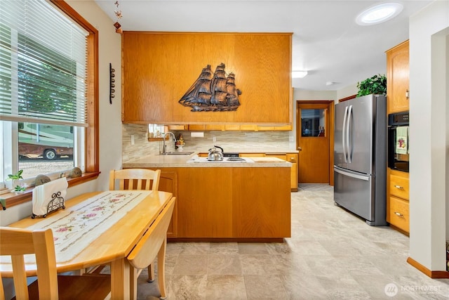 5722 44th Ave E, Tacoma, WA 98443 - kitchen featuring freestanding refrigerator, a peninsula, a sink, decorative backsplash, and black oven