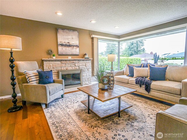 1709 NW 99th St, Seattle, WA 98117 - living area featuring wood finished floors, a textured ceiling, a stone fireplace, and baseboards