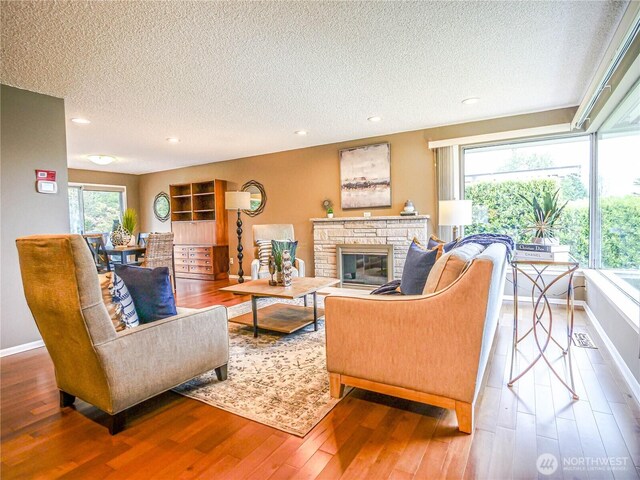 1709 NW 99th St, Seattle, WA 98117 - living area with a textured ceiling, wood finished floors, a fireplace, recessed lighting, and baseboards