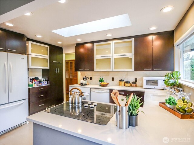 1709 NW 99th St, Seattle, WA 98117 - kitchen with white appliances, a skylight, a sink, light countertops, and tasteful backsplash