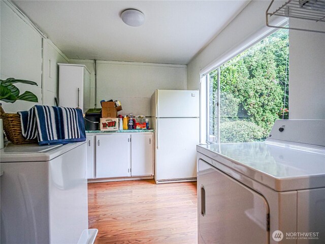 1709 NW 99th St, Seattle, WA 98117 - kitchen featuring freestanding refrigerator, light wood-style flooring, white cabinetry, washing machine and dryer, and light countertops