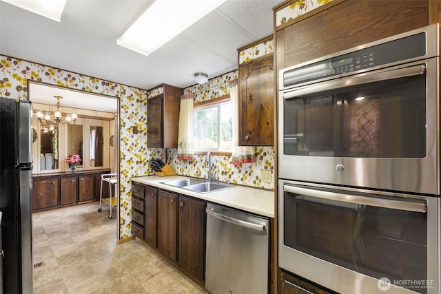 1171 E Trails End Dr, Belfair, WA 98528 - kitchen featuring appliances with stainless steel finishes, wallpapered walls, light countertops, dark brown cabinets, and a chandelier