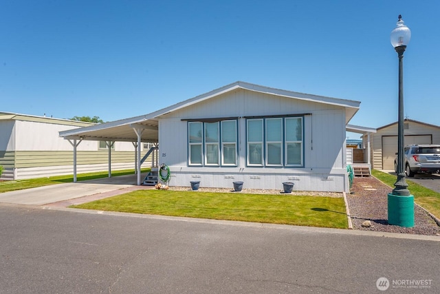 2240 W Broadway Ave Unit 25, Moses Lake, WA 98837 - manufactured / mobile home featuring a front yard, an outdoor structure, concrete driveway, and an attached carport