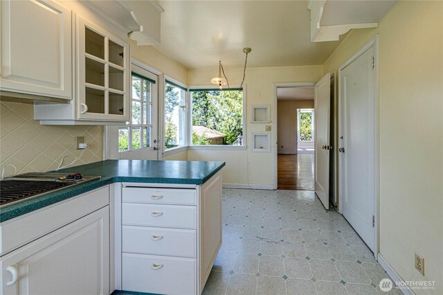 1415 E 2nd St, Port Angeles, WA 98362 - kitchen featuring dark countertops, glass insert cabinets, a peninsula, decorative backsplash, and white cabinetry