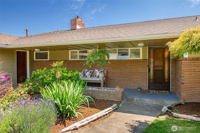 2483 Hilltop Rd, Ferndale, WA 98248 - view of exterior entry with brick siding, a chimney, and a shingled roof