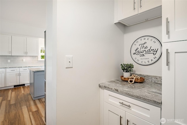2483 Hilltop Rd, Ferndale, WA 98248 - kitchen with light wood-style floors, white cabinetry, backsplash, and light stone counters