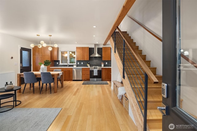 3659 Whitman Ave N, Seattle, WA 98103 - kitchen with stainless steel appliances, wall chimney exhaust hood, brown cabinetry, light countertops, and light wood finished floors