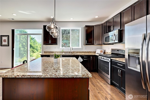 21598 NW Monterey Loop, Poulsbo, WA 98370 - kitchen with stainless steel appliances, light wood finished floors, light stone counters, a kitchen island, and recessed lighting