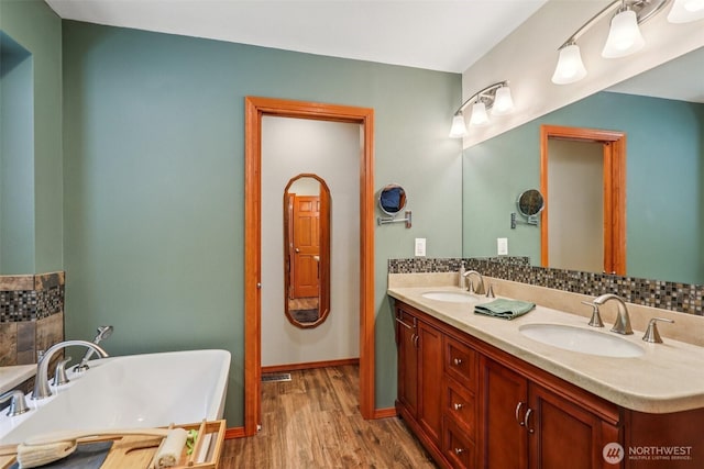 6611 Menzel Lake Rd, Granite Falls, WA 98252 - bathroom featuring double vanity, a soaking tub, wood finished floors, and decorative backsplash