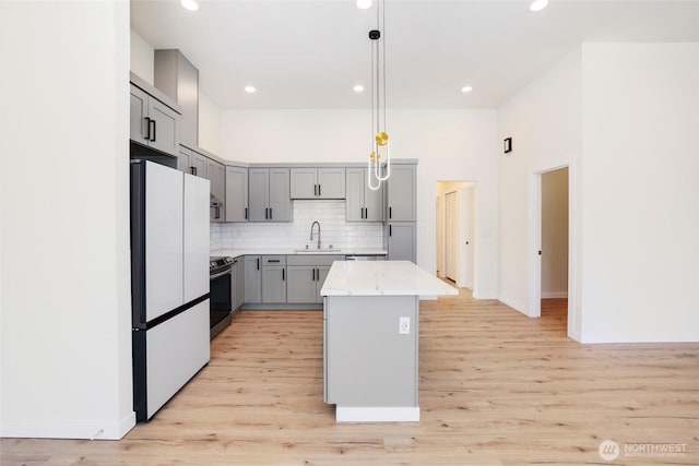 3124 Oas Dr W, University Place, WA 98466 - kitchen with freestanding refrigerator, gray cabinetry, stainless steel electric stove, light wood-type flooring, and backsplash