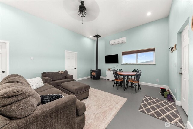 40359 Barbara Ln N, Davenport, WA 99122 - living room with a wood stove, ceiling fan, a wall mounted AC, concrete floors, and baseboards