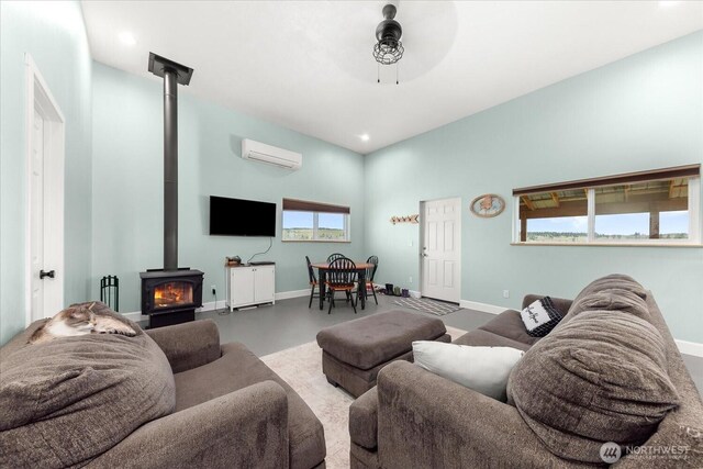 40359 Barbara Ln N, Davenport, WA 99122 - living area featuring a wood stove, a wall mounted air conditioner, baseboards, recessed lighting, and finished concrete floors
