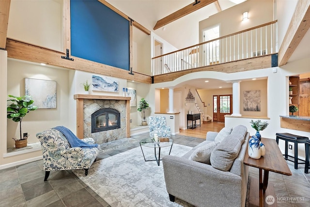 8495 Landing Ln SE, Port Orchard, WA 98367 - living room with stairway, a high ceiling, a premium fireplace, ornate columns, and beam ceiling
