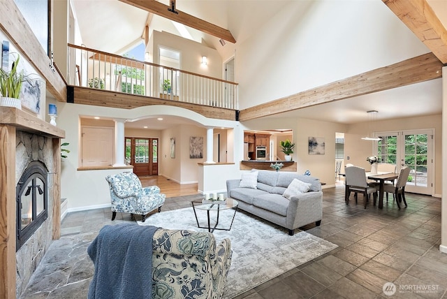 8495 Landing Ln SE, Port Orchard, WA 98367 - living area with stone tile floors, high vaulted ceiling, a glass covered fireplace, decorative columns, and beamed ceiling