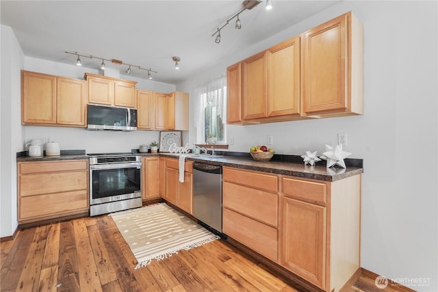1910 192nd Avenue Ct SW, Lakebay, WA 98349 - kitchen with light brown cabinetry, stainless steel appliances, dark countertops, light wood-style flooring, and rail lighting