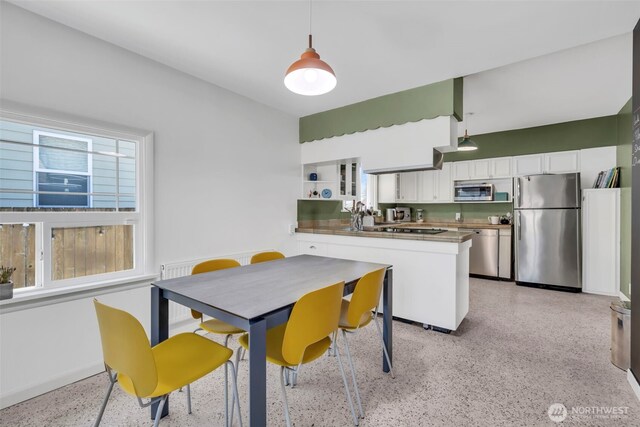 8554 16th Ave NW, Seattle, WA 98117 - kitchen with appliances with stainless steel finishes, dark speckled floor, white cabinets, a peninsula, and hanging light fixtures