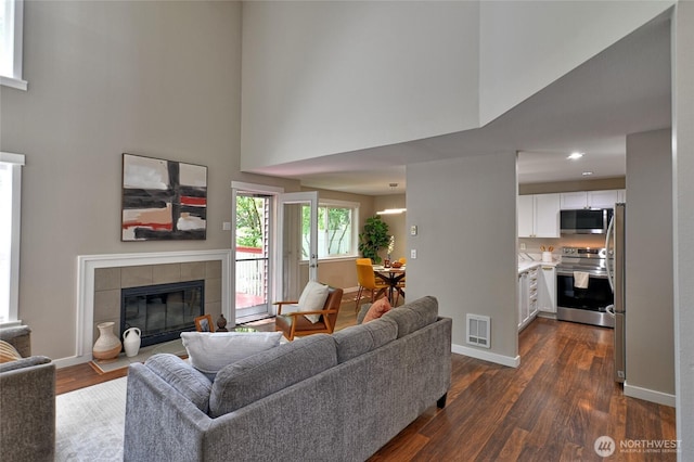 3030 128th Ave SE Unit 6, Bellevue, WA 98005 - living area with a towering ceiling, a tiled fireplace, and dark wood-style floors