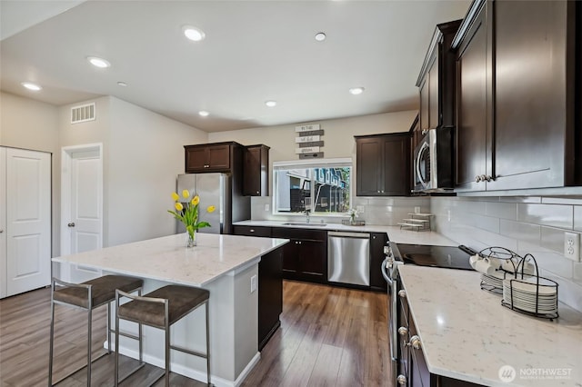 17401 118th Avenue Ct E Unit A, Puyallup, WA 98374 - kitchen featuring appliances with stainless steel finishes, dark brown cabinetry, tasteful backsplash, a kitchen breakfast bar, and a center island