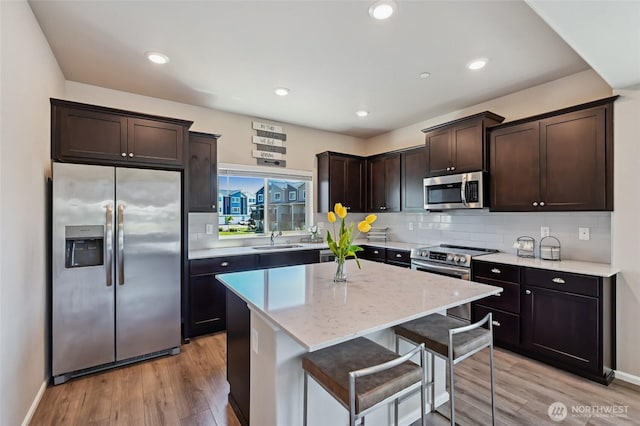 17401 118th Avenue Ct E Unit A, Puyallup, WA 98374 - kitchen with appliances with stainless steel finishes, dark brown cabinets, light wood-style floors, backsplash, and a kitchen island