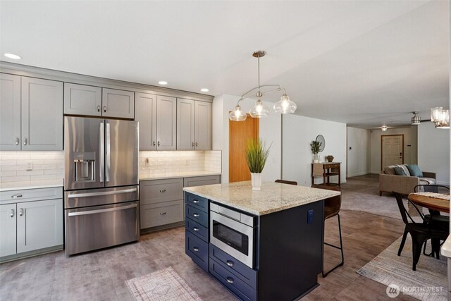 29664 127th Pl SE, Auburn, WA 98092 - kitchen featuring appliances with stainless steel finishes, gray cabinets, a breakfast bar, tasteful backsplash, and pendant lighting