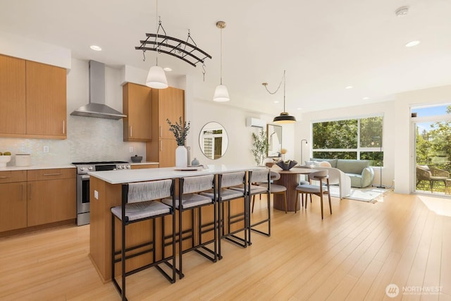 5175 42nd Ave S, Seattle, WA 98118 - kitchen with wall chimney range hood, stainless steel range, light wood-style floors, a breakfast bar area, and decorative backsplash