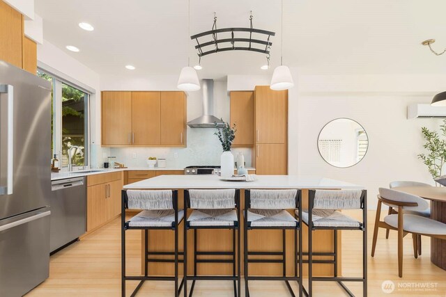 5175 42nd Ave S, Seattle, WA 98118 - kitchen featuring appliances with stainless steel finishes, wall chimney exhaust hood, light wood-style flooring, a breakfast bar, and a wall mounted AC