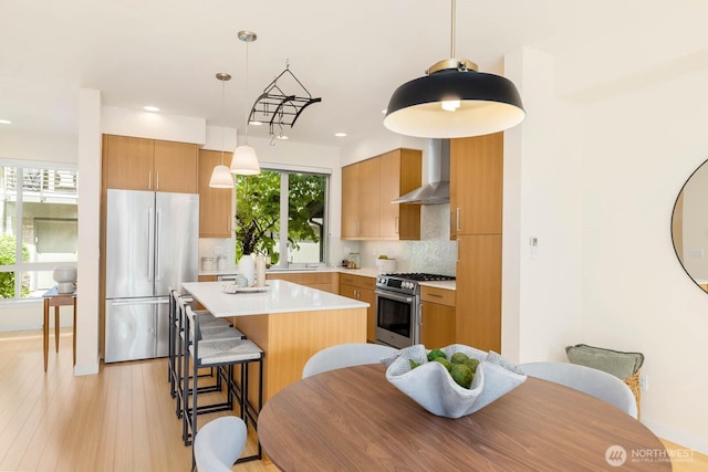 5175 42nd Ave S, Seattle, WA 98118 - kitchen featuring appliances with stainless steel finishes, a center island, tasteful backsplash, wall chimney range hood, and a breakfast bar