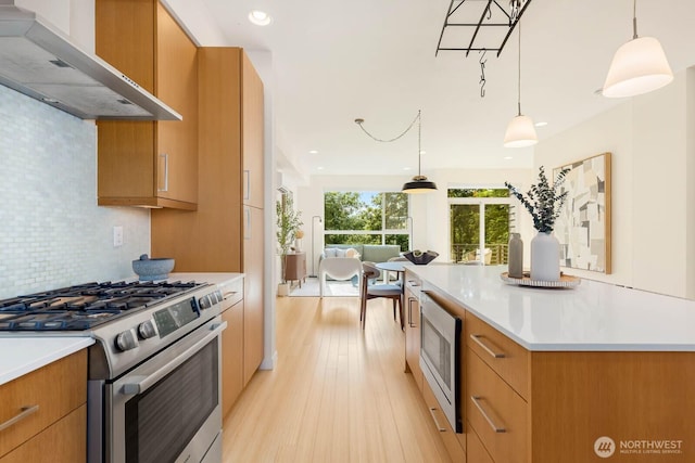 5175 42nd Ave S, Seattle, WA 98118 - kitchen with appliances with stainless steel finishes, wall chimney exhaust hood, light wood-type flooring, backsplash, and light countertops