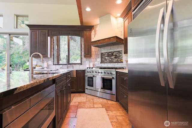 180 Country River Ln, Entiat, WA 98822 - kitchen featuring stainless steel appliances, wall chimney exhaust hood, stone tile floors, backsplash, and recessed lighting