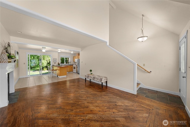 2502 218th St E, Spanaway, WA 98387 - unfurnished living room with lofted ceiling, stairway, light wood-style flooring, and a fireplace with raised hearth