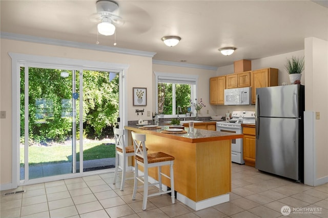 2502 218th St E, Spanaway, WA 98387 - kitchen featuring white appliances, a breakfast bar, a ceiling fan, a peninsula, and light tile patterned floors