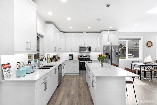 4123 Stuart Cir, Ferndale, WA 98248 - kitchen featuring stainless steel appliances, a breakfast bar, light wood-style flooring, white cabinets, and recessed lighting