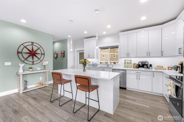 4123 Stuart Cir, Ferndale, WA 98248 - kitchen featuring stainless steel dishwasher, range, a breakfast bar, white cabinets, and light wood-style floors